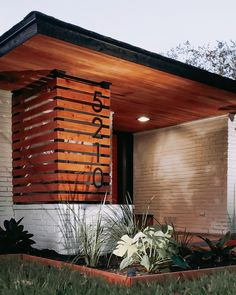 a modern house with wood slats on the side and plants in the front yard