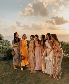 a group of women standing next to each other on top of a grass covered field