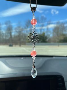 a car dashboard with a necklace hanging from it's dash board and the sunroofer in the background