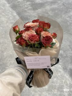 a person holding a bouquet of roses in their hand with a price tag on it