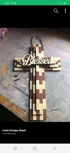 a wooden cross sitting on top of a table next to a wall with the word blessed carved into it