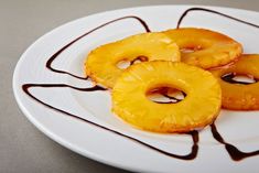 three pieces of pineapple on a white plate with chocolate drizzle