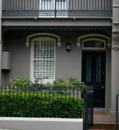 a grey house with white shutters and black gate