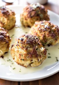 four crab cakes are on a white plate