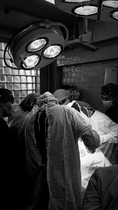 black and white photograph of doctors in operating room with lights on above the beds,