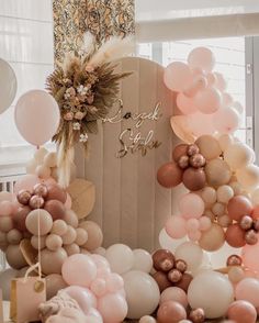 there are many balloons in the shape of an arch and some flowers on top of it