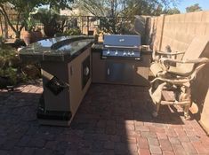 an outdoor kitchen with grill, sink and chairs