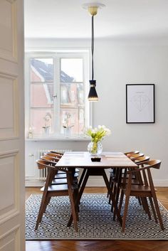 a dining room table and chairs in front of a window with an art work on the wall