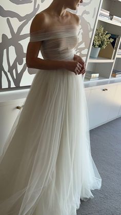 a woman in a white dress standing next to a wall