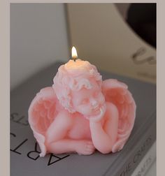 a candle that is sitting on top of a book with an angel figurine