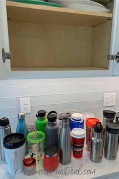 there are many different cups on the counter in this kitchen sink, and one is full of them