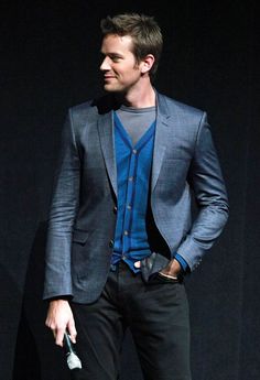 a man in a blue shirt and black pants is holding a white umbrella while standing on stage