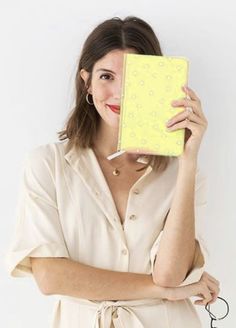 a woman is holding up a yellow box