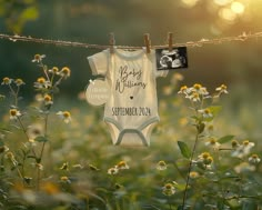 a baby's announcement hanging on a clothesline in a field with wildflowers