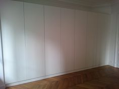 an empty room with white walls and wood floors