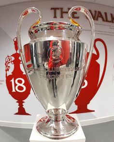 the soccer trophy is on display in front of a red and white wall with an advertisement behind it