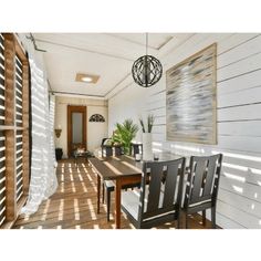 a dining room table and chairs in front of a white wall with wood slats