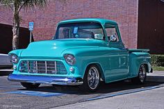 an old blue truck parked in front of a brick building