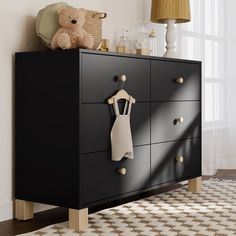 a baby's clothes hanging on a black dresser