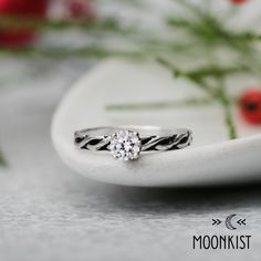 a close up of a ring on a plate with red flowers in the back ground