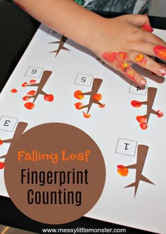 a child's hand on top of a fingerprint counting game with the words falling leaf