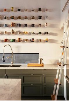 a kitchen with marble counter tops and shelves filled with coffee mugs on the wall