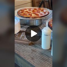 a pizza sitting on top of a wooden table next to bottles of milk and condiments