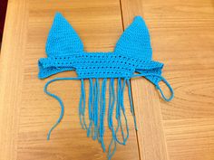 a blue crocheted hat with ears and tail on top of a wooden table