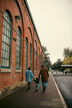 a man and woman walking down the street with a small child in their arms holding hands