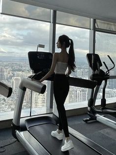 a woman is standing on a treadmill looking out the window