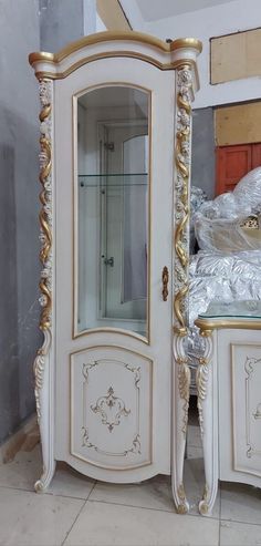 an ornate white and gold armoire with glass doors