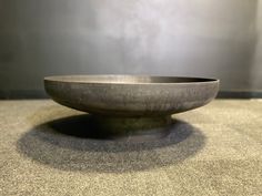 a large metal bowl sitting on top of a counter next to a wall and floor