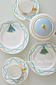 four tea cups and saucers decorated with blue, green and gold trimmings