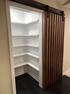 an empty white pantry with sliding doors and wood slats on the door, is shown