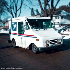 an ice cream truck is driving down the street in front of some houses and trees