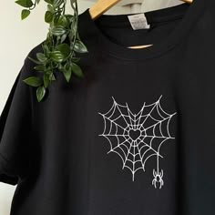 a black t - shirt with white spider web on it