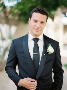 a man in a tuxedo is posing for a photo with his hand on his hip