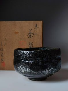 a black bowl sitting on top of a table next to a wooden box with writing on it