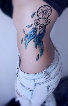 a woman with a tattoo on her stomach has a blue dream catcher design on it