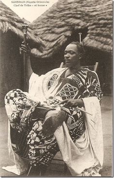 an old black and white photo of a person sitting on a chair holding a stick