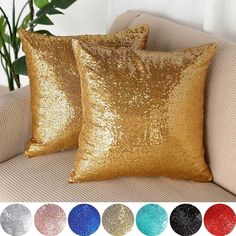 two gold sequin pillows sitting on top of a couch in front of a potted plant