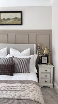 a bed with white sheets and pillows in a bedroom next to a painting on the wall