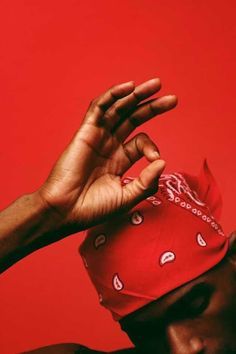 a man wearing a red bandana with his hand in the air