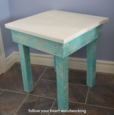 a small white table sitting on top of a tile floor next to a blue wall