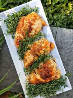 two pieces of chicken with herbs on a white plate