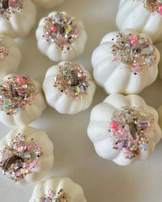 white pumpkins decorated with glitter and sprinkles are arranged on a table