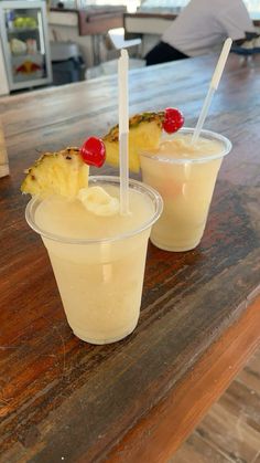 two cups filled with drinks sitting on top of a wooden table