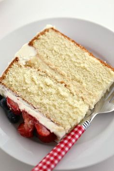 a slice of cake on a plate with strawberries and blueberries