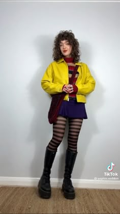 a woman in yellow jacket and purple skirt posing for the camera with her hands on her hips