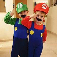 two children in mario and luigi costumes posing for the camera with their thumbs up signs